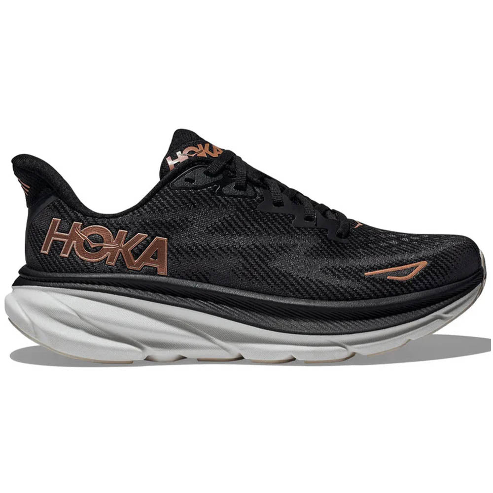 Side view on white background of Womens Hoka Clifton running shoe in Black/Rose Gold, Wide width